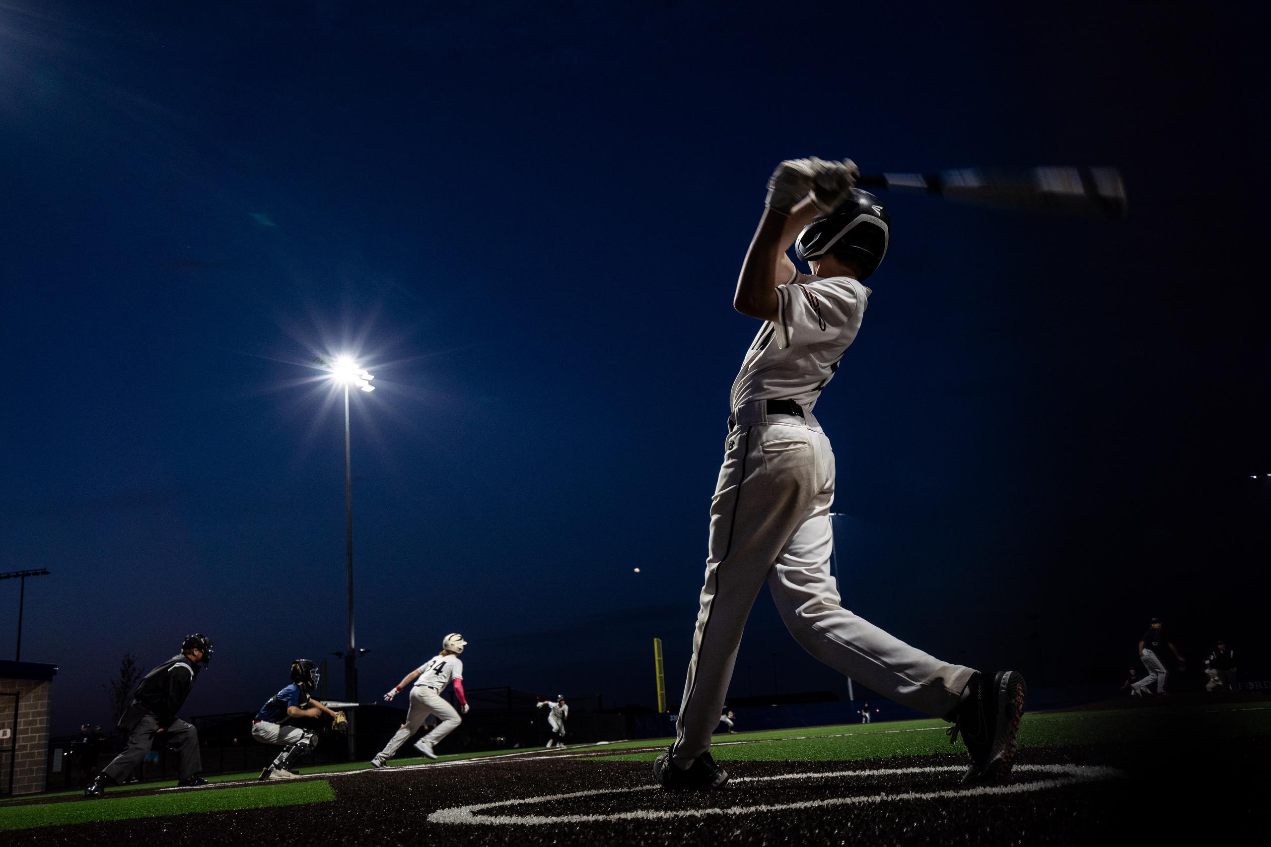 Baseball player hitting ball at night